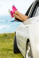 Car Travel Vacation And Relax Concept. Woman Legs Out The Windows Enjoying Freedom And Relaxing On Nature Coast Landscape.