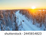 Car travels the icy and empty road crossing the boreal snowy forest at sunrise, Swedish Lapland, Sweden, Scandinavia, Europe