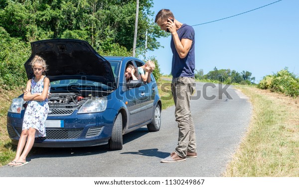 Car trouble. Man calling road service on\
holiday with broken car on\
vacation.