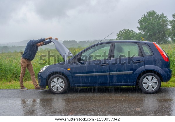 Car trouble in the rain.\
Broken car.