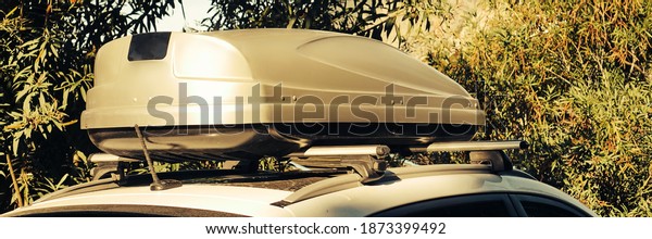 Car Trunk Box On Roof. Car With Luggage Box On
Rooftop Fastening To The Rack System. Closeup View Of Car Roof Box
On Rooftop. Travel And Trip Auto Tourism Landscape With Mountain
And Sea Beach.