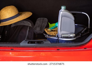 Car trunk packed with vacation essentials like a straw hat and luggage, alongside important travel safety equipment including engine oil, a flashlight, and jumper cables, ready for a secure journey