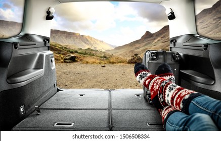 Car Trunk And Woman Legs With Autumn Socks. Free Space For Your Decoration And Black Suitcase. 