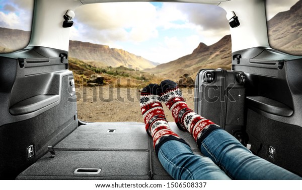 Car trunk and woman legs\
with autumn socks. Free space for your decoration and black\
suitcase. 