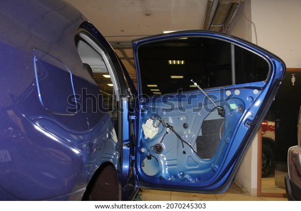Car tuning. Disassembled car. Disassembled\
blue car door for installation of acoustic components and noise -\
vibration isolation. Disassembly of doors before sound\
insulation.