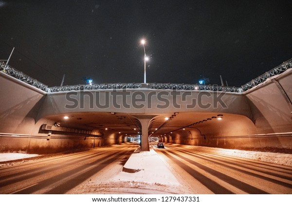 Car tunnel under the bridge lit in the dark.\
Road junction.
