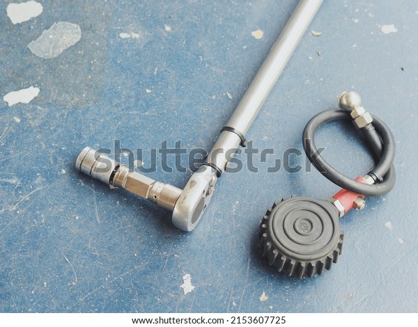 Car tyre pressure\
check tool and nut unlock tool on the workshop floor. Garage tools\
concept. Selective focus.