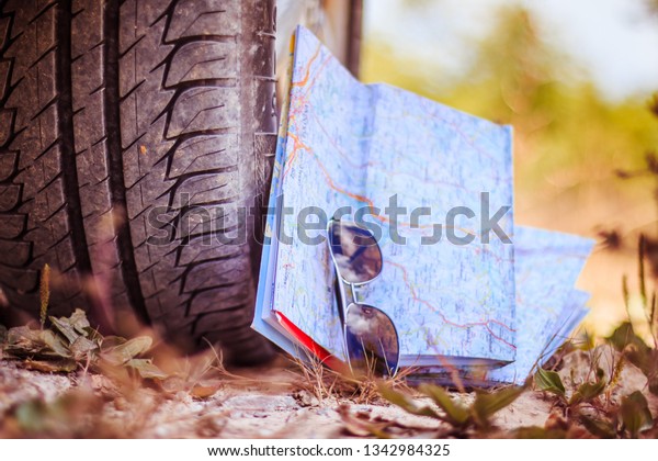 Car\
tyre, sunglasses and roadmap on sandy ground,\
desert