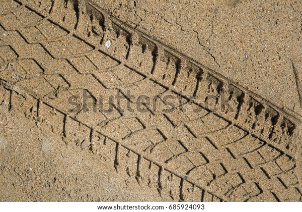 Car tyre tracks over a\
sandy beach