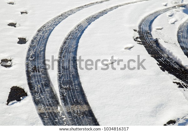 Car tyre\
tracks in snow with foot prints\
nearby