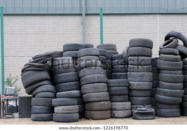 Car tyres stacked recycling compound environment\
old used rubber black