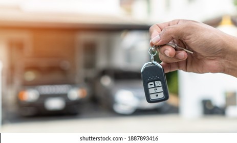 Car valet parking service enterprise, car rental, or automobile insurance business concept with owner or person handling vehicle remote key on blur parking garage background