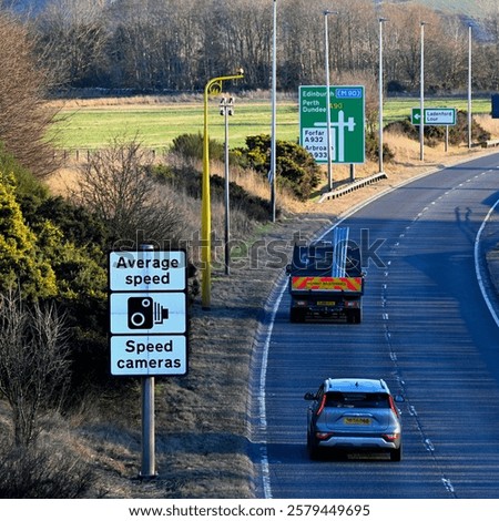 A car and a van pass an Average Speed camera on the southbound A90 dual carriageway at Forfar, Scotland, on a sunny day in winter.