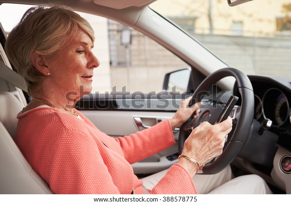 In car\
view of senior female driver using\
smartphone