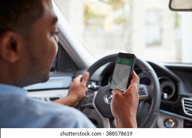 In Car View Of Young Male African American Looking At Maps App On His Phone