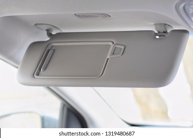 Car Visor. Car Interior. Grey Open Sun Car Visor With Selective Focus And Car Mirror On Blurred Background With Automobile Window