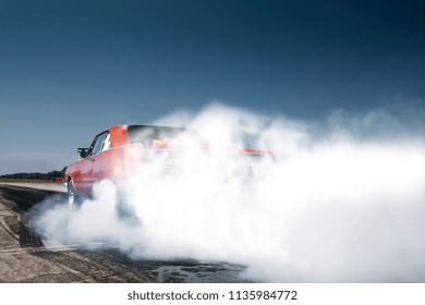 Car warmup with smoke before the drag race. Burnout and drift at the starting line. Racecar doing a lot of smoke on the starting line. Muscle car full throttle at the show