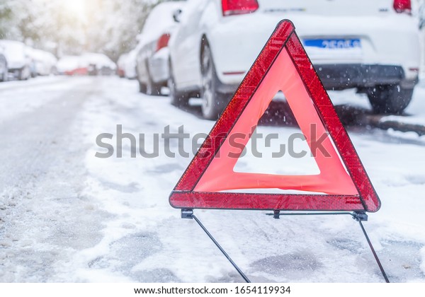 Car warning triangle on the road against the city\
in the evening
