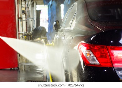 Car Wash, Black Car In Automatic Car Wash, Rotating Red And Blue Brush. Washing Vehicle.