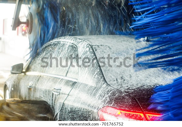 Car wash, black car in automatic car\
wash, rotating red and blue brush. Washing\
vehicle.