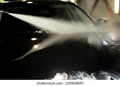 Car Wash. Black Car In Car Wash. Hot Water Jet. Washing Off Dirt From Vehicle.