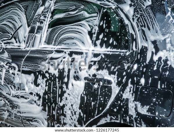 Car wash bubbles with soap. Close up of car\
washing process. Abstract\
background.