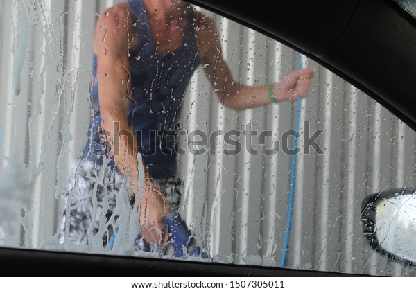 car wash. Clean and wash the car window.\
Drops of water on the glass. Man\
washes.