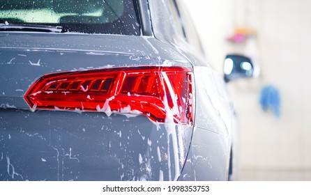 Car wash concept. Front view of white sports car covered with water, washing foam, and soap on hood and bumper. Professional car detailing and commercial cleaning service concept. Wet car background - Shutterstock ID 1998353753