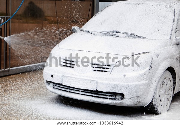 Car wash with\
foam in car wash station. Carwash. Washing machine at the station.\
Car washing concept. Car in\
foam.