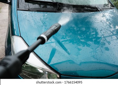 Car Wash At Home Alone. Car Wash High Pressure Close-up. A Man Washes A Green Car.