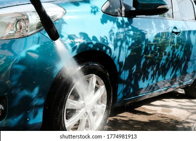 Car Wash At Home Alone. Car Wash High Pressure Close-up. A Man Washes A Green Car.