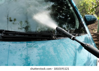 Car Wash At Home Alone. Car Wash High Pressure Close-up. A Man Washes A Green Car.