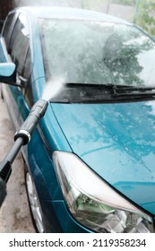 Car wash at home alone. Car wash high pressure close-up. A man washes a green car.