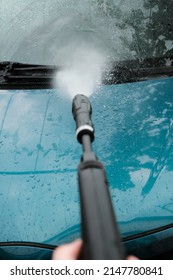 Car wash at home alone. Car wash high pressure close-up. A man washes a green car.