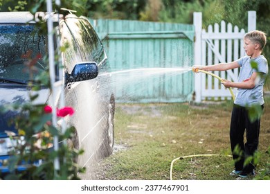 Car wash at home. Boy earns pocket money by washing cars with a hose - Powered by Shutterstock