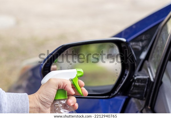 car wash and interior chemical\
cleaning concept.woman hand use microfiber cloth and spray to clean\
lateral door from inside,retractable rear view mirror,steering\
wheel.modern hybrid vehicle clean\
home
