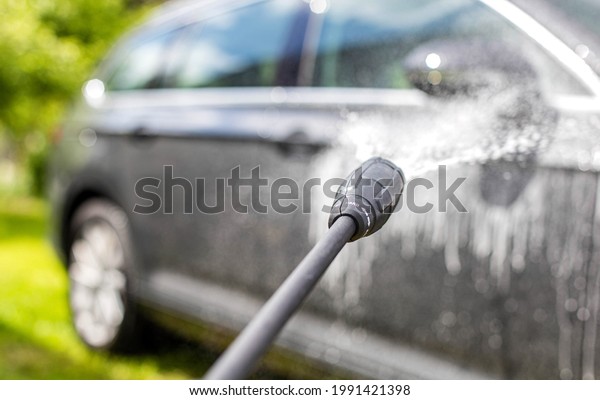 Car wash with modern car shampoo using a high\
pressure washer in summer. Background, cleaning cars from dirt,\
reflection