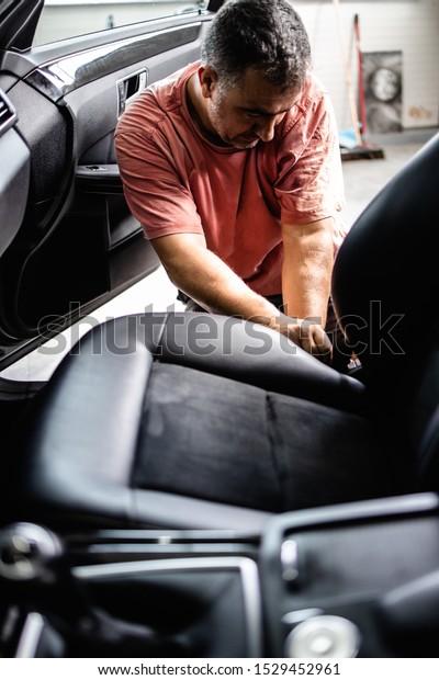 Car wash service worker wet cleaning vehicle\
interior and seats
