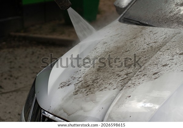 Car wash. The car is washed under the pressure of a\
jet of water. Using a water spray to wash off dirt from the surface\
of the car.