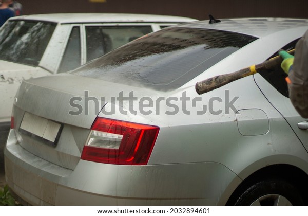 Car wash. The car is washed under the pressure of a\
jet of water. Using a water spray to wash off dirt from the surface\
of the car.