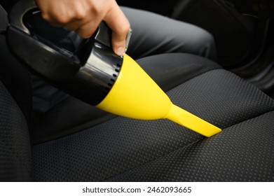 Car wash worker cleans fabric upholstery of car seat from dust and dirt with portable car vacuum cleaner, close-up. Concept of cleanliness in car interior, cleaning - Powered by Shutterstock