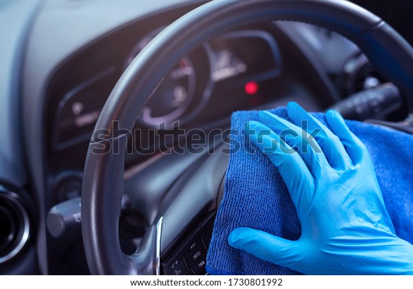 car wash,  worker hand wear glove\
cleaning console steering wheel with microfiber cloth blue. hygiene\
prevention  antibacterial of corona virus\
outbreak.