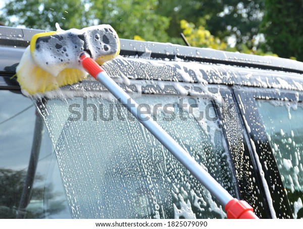 Car wash with\
a yellow brush with car\
shampoo.