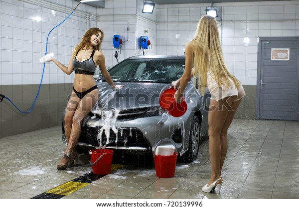 Car\
Wash. Young sexy woman in blue jeans short washes\
car