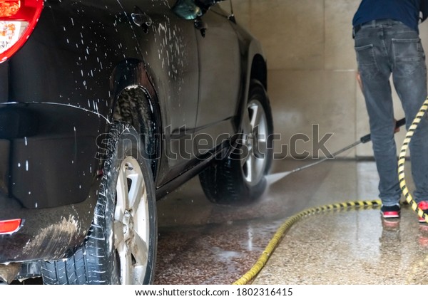 Car washing. Cleaning car with high pressure water\
and foam