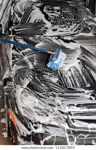 Car\
washing. Cleaning modern car covered by\
foam.