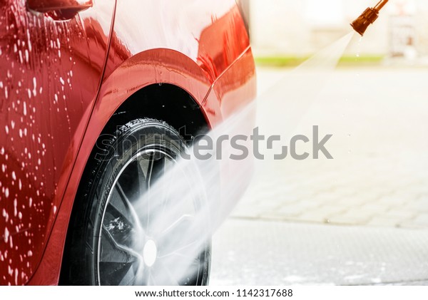 Car washing concept.\
Cleaning vehicle wheel or rim using high pressure water. Selective\
detail focus.