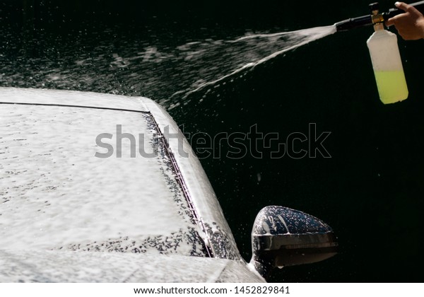 Car washing with
high pressure water jet. Water and foam under pressure flies toward
the car body. Close-up view