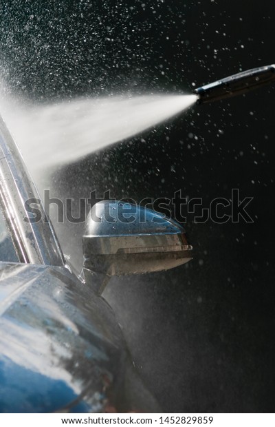 Car washing with\
high pressure water jet. Water and foam under pressure flies toward\
the car body. Close-up view