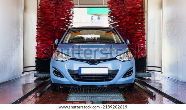 Car washing machine. Auto brush washer clean\
blue car on automatic carwash station. Automated car washing\
machine background